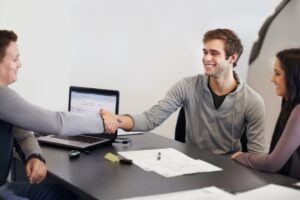 Sealing the deal. Young couple in a car salemans office signing paperwork for a new car.