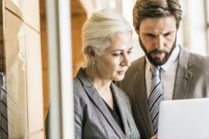 Businesspeople wearing suits looking at laptop