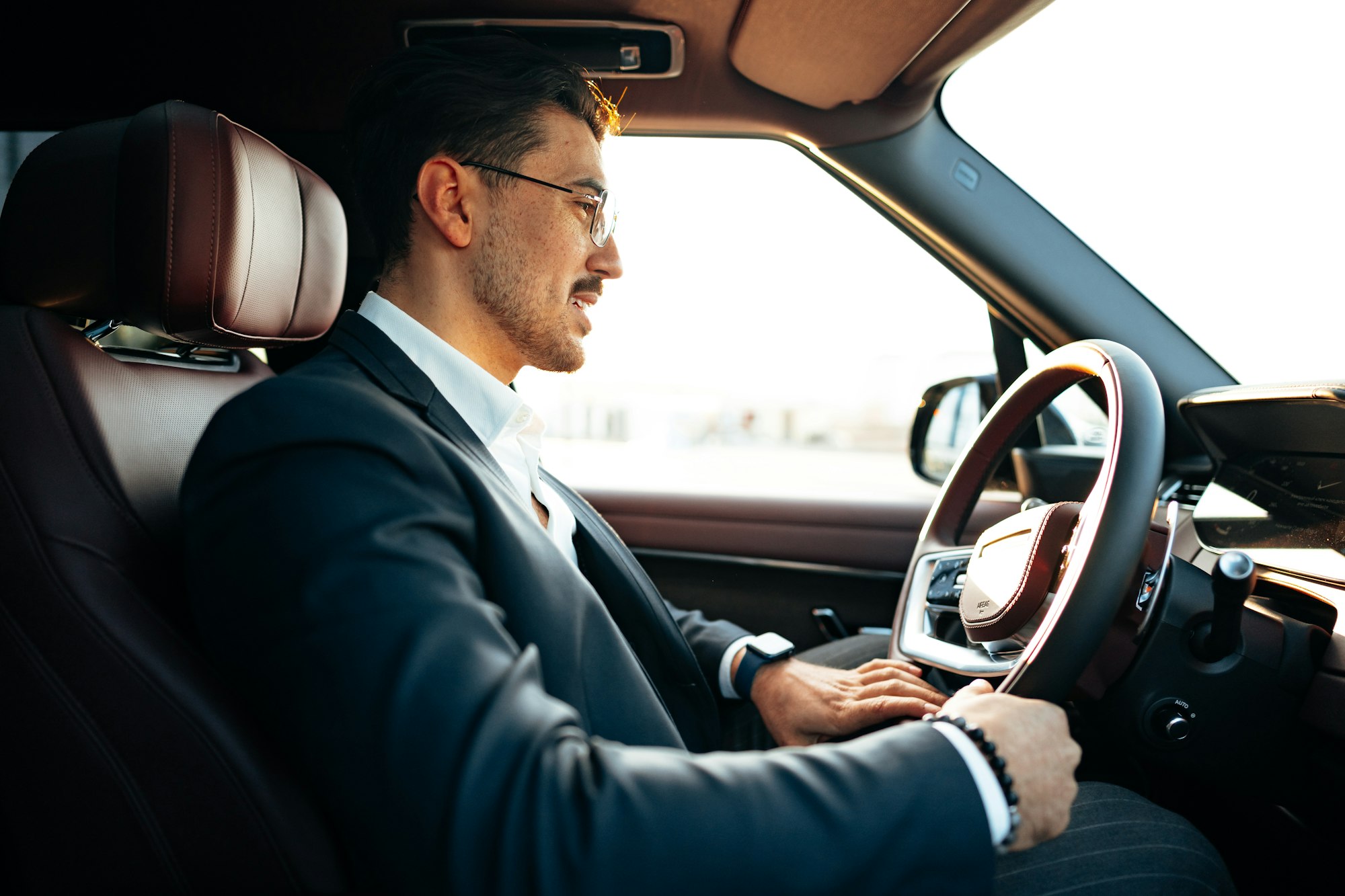 Young businessman in elegant suit driving luxury car